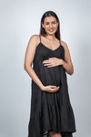 Angled pose of black maternity layered high-low dress with spaghetti straps, showcasing the flowy design and comfortable fit for moms-to-be.