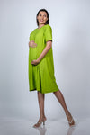 Full-body front left leaning view of the Neon Green Maternity A-Line T-Shirt Dress, highlighting the dress's flow and slit detail.