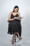 Seated view of black maternity layered high-low dress with spaghetti straps, showcasing its comfortable and chic design for moms-to-be.
