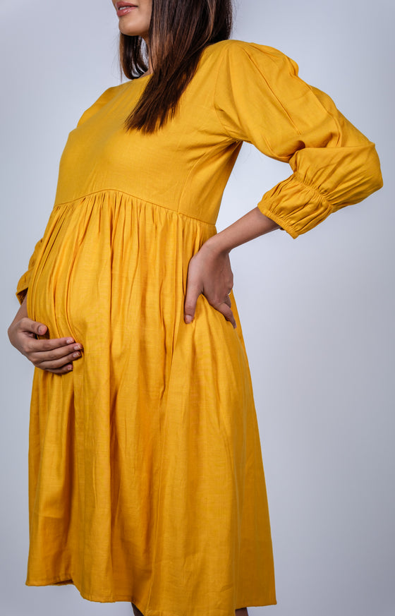 Angled close-up view of Mustard Yellow Fit & Flare Maternity Dress, featuring stylish gathers and a flattering fit for moms-to-be.