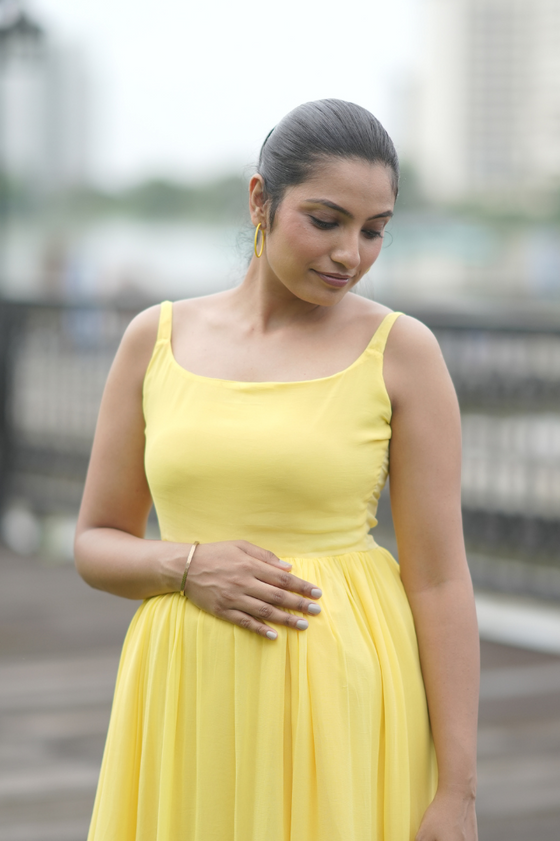 Angled view of Sun-Kissed Ombre Maternity Evening Gown, showcasing the vibrant yellow-to-blue ombre and comfortable fit, perfect for evening strolls.