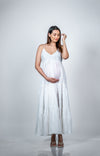 Angled view of a white maternity dress with spaghetti straps, highlighting its flowy silhouette and elegant fit for moms-to-be.